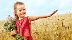 Милая маленькая девочка в пшеничном поле с букетом цветов